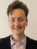 woman with short dark hair wearing an open collared striped shirt with suit jacket.