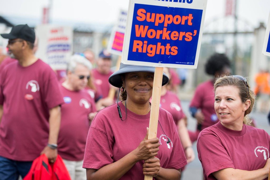 “Healthy People 2030 SDOH Graphic.png’” by U.S. Department of Health and Human Services, Office of Disease Prevention and Health Promotion is in the Public Domain. Access for free at https://health.gov/healthypeople/objectives-and-data/social-determinants-health. Photo showing union workers protesting with signs